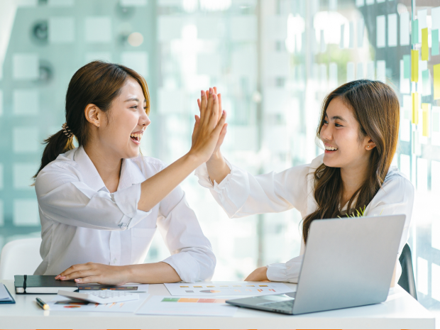 Two colleagues in a conference room giving each other a high five
