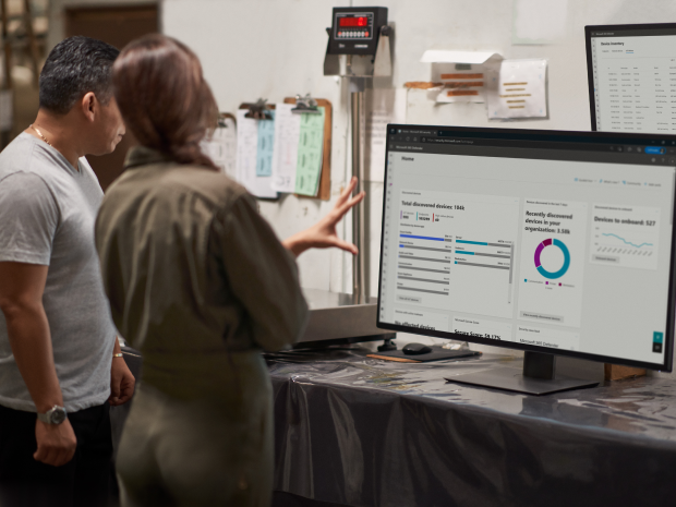 Two people standing and looking at a computer monitor
